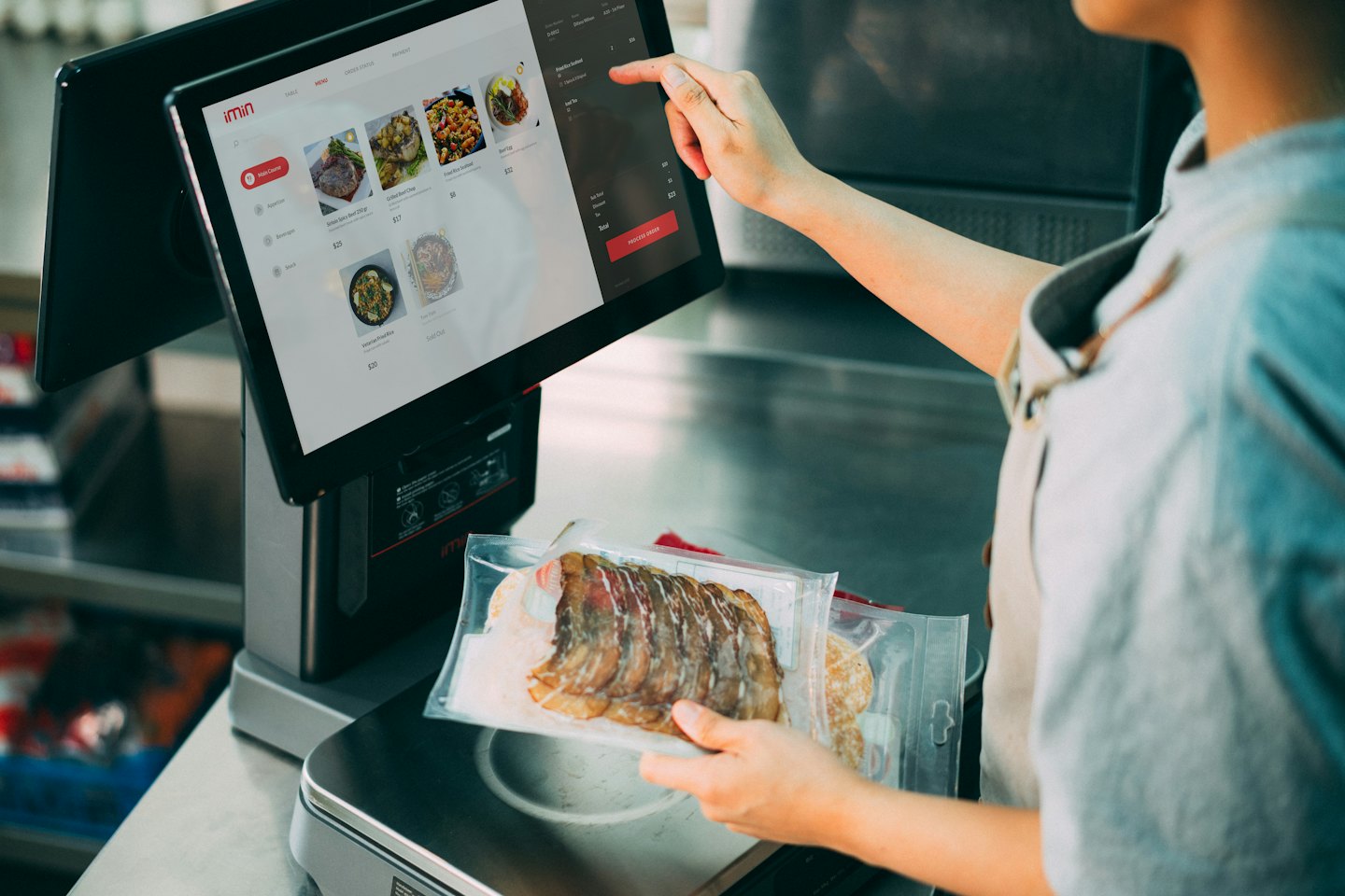 Employee weighs vacuum sealed food packages on a digital scale.