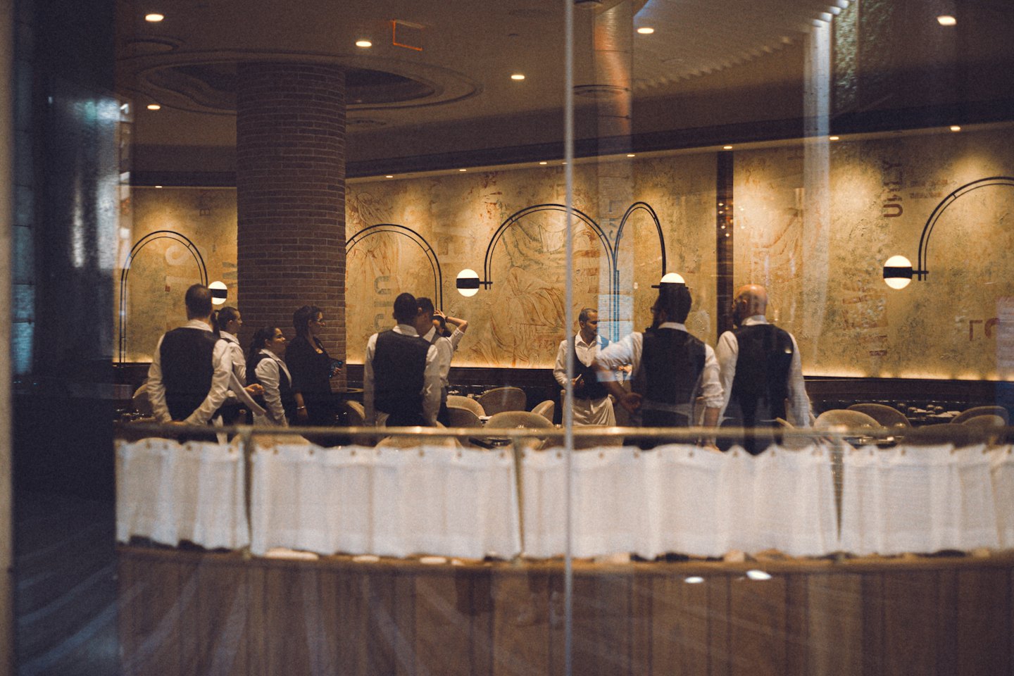 Restaurant staff gather for a pre-service briefing in the dining room.