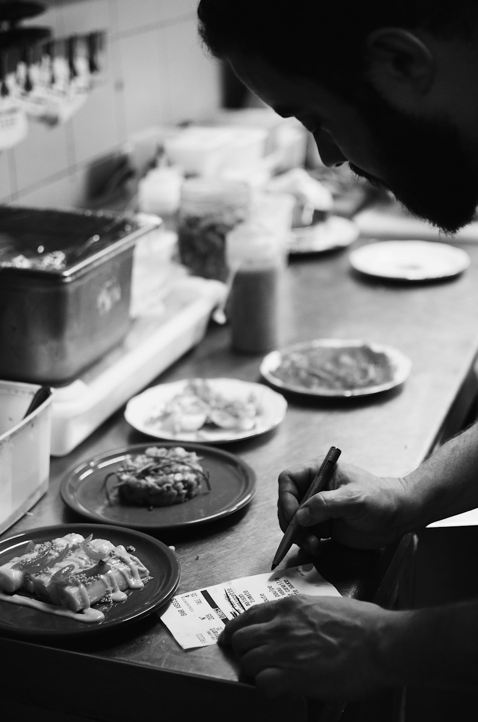 Chef reviews order ticket with prepared food on kitchen counter.
